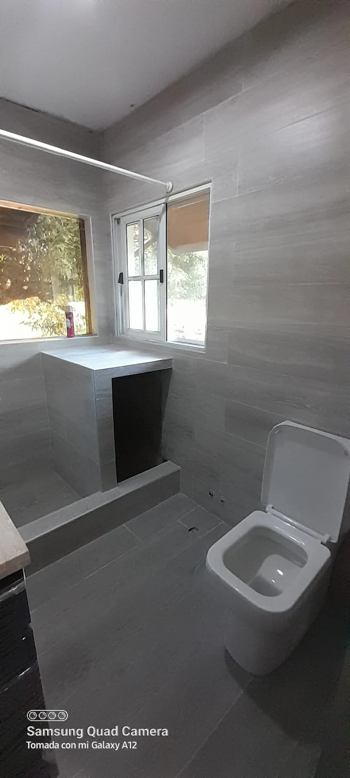 Baño renovado con revestimientos grises, mesada y espejo