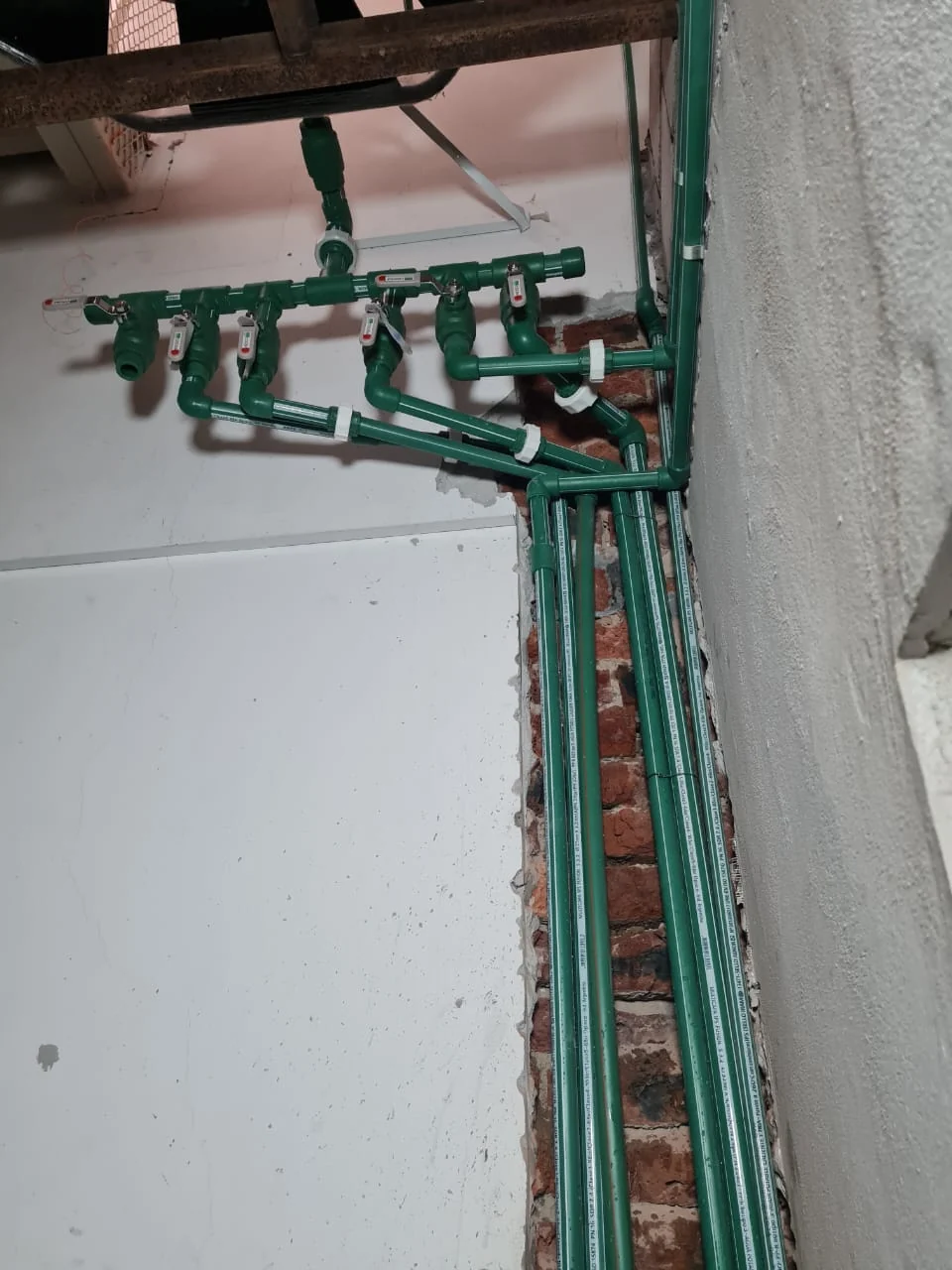 Instalación de cañerías verdes en una pared durante la obra