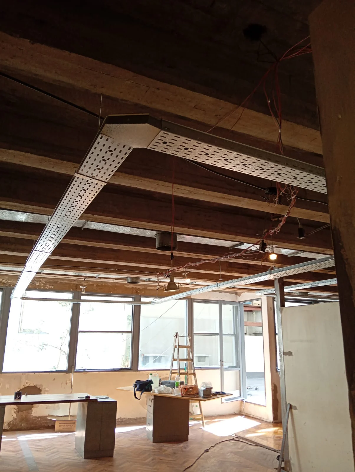Interior en obra con estructura de madera y perfiles metálicos